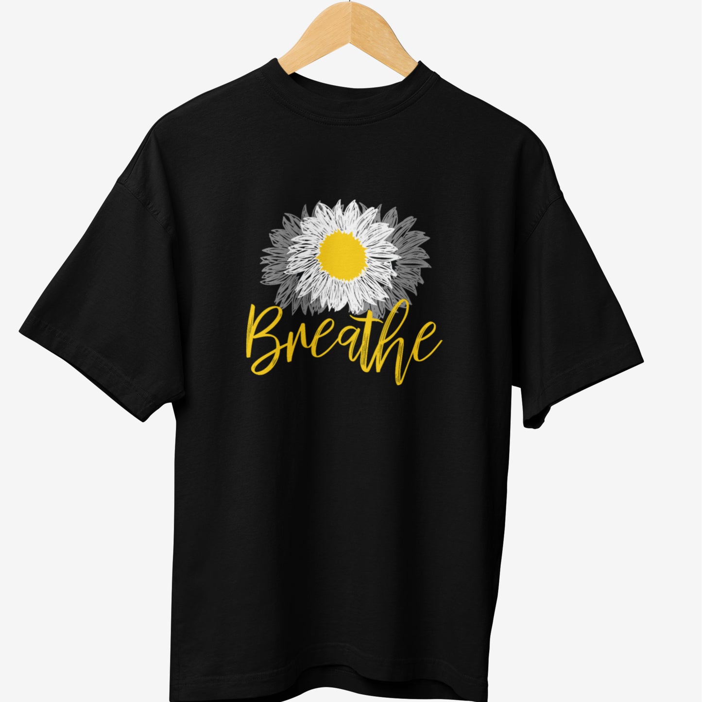 Black yoga t-shirt featuring a hand-drawn daisy with a yellow center and white-to-gray petals, accompanied by the word 'Breathe' in elegant yellow script, promoting mindfulness and relaxation.