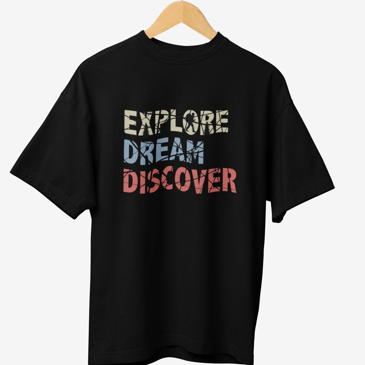 Black travel t-shirt featuring the motivational phrase 'EXPLORE DREAM DISCOVER' in bold, distressed typography with silhouettes of travelers and adventure elements inside the letters.