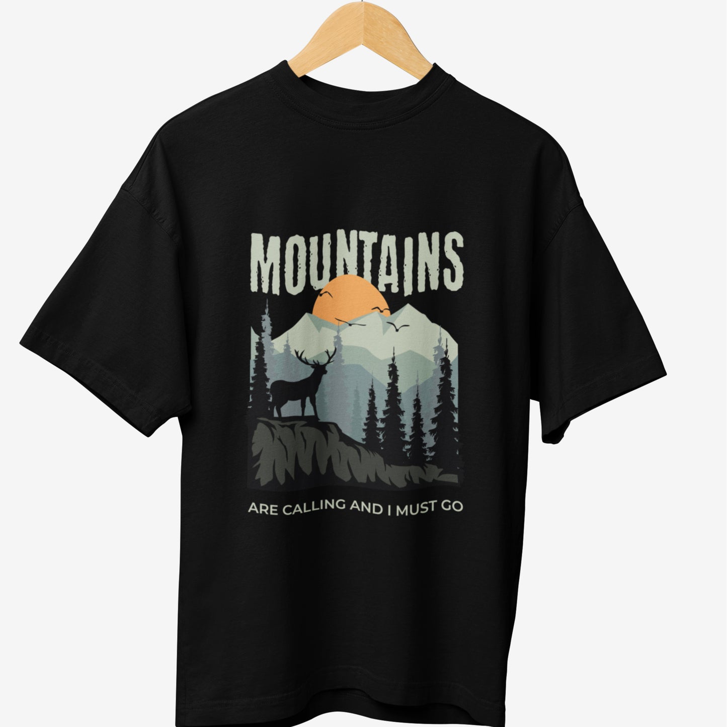 Black travel t-shirt featuring a scenic mountain landscape with a deer silhouette and the quote 'MOUNTAINS ARE CALLING AND I MUST GO,' ideal for nature lovers and adventure seekers.