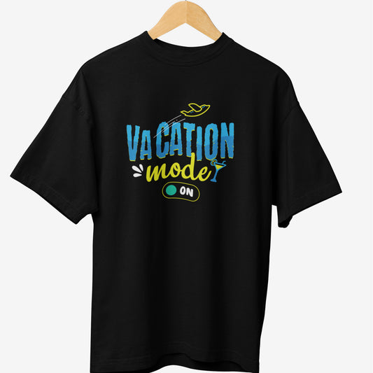 Black travel t-shirt featuring the phrase 'VACATION mode ON' in blue and yellow typography, with an airplane, a cocktail glass, and a switch icon representing relaxation and travel vibes.